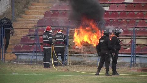 Team of firefighters trying to put out fire on plastic chairs in a stadium b Stock Footage 145483078