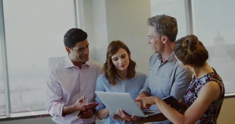 Team of four leaning, man pointing at laptop causing chart overlays, reviewing Stock Footage 333830195