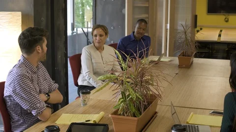 Team of four office workers sitting at meeting table. 動画素材 88104777