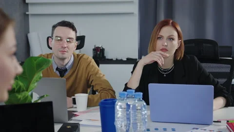 A team of four people discusses work issues sitting at a desk in the office Stock Footage 193972005