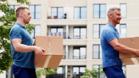Team of Happy Movers Delivering Parcels and Boxes Outside a Truck on a Sunny Day Stockbeeldmateriaal 279218997