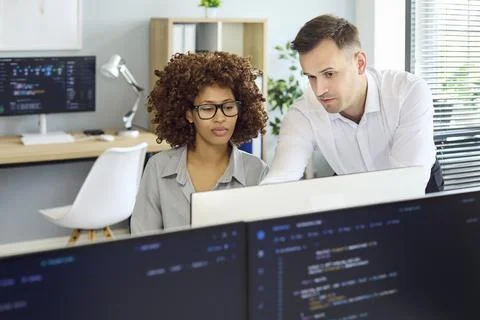 Team lead mentoring junior developer at monitor in bright tech office setting Stock Photos