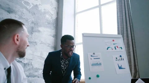 Team leader black man brainstorms and dances using company graphs and statistics Stock Footage 125635311