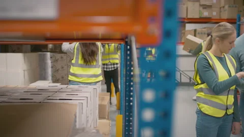 Team Leader With Digital Tablet In Busy Warehouse Training Female Intern Stock Footage 179674791