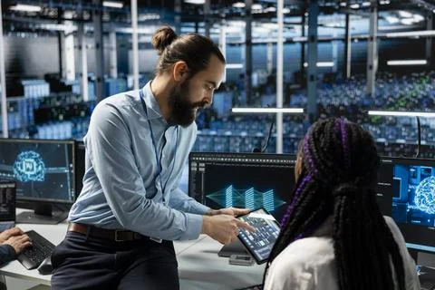 Team leader guides intern in data center to troubleshoot issues using AI Stock Photos