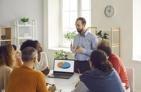 Team leader making presentation in group meeting using pie charts on laptop Foto stock