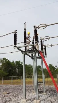 Team of lineman electrician workers using red extension ladder performing . Stock Photos