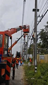 Team of lineman electrician workers using orange crane bucket truck. Stock Photos