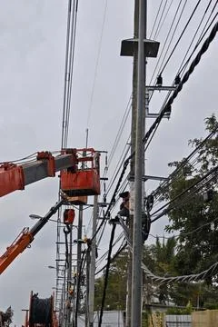 Team of lineman electrician workers using orange crane bucket truck. Stock Photos