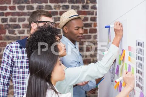 Team looking at sticky notes on wall Stock Photos
