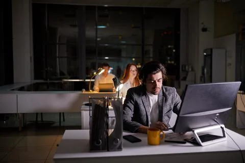 Team of managers office workers working on project very late, using computer Stock Photos