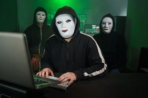 Team of Masked Hackers Using Computer to inflict Data Breach Attack on 写真素材