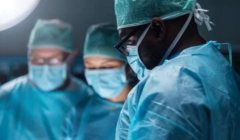 Team of medical doctors performs surgical operation in modern operating room Stock Photos