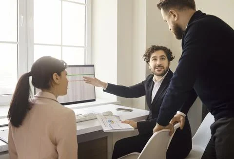 Team meeting with analytics dashboard and report discussion in modern office Stock Photos