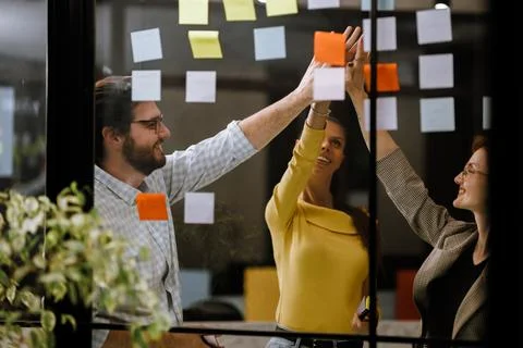 Team members collaborating on brainstorming session using sticky notes in modern Stock Photos
