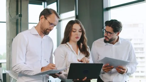 Team members collaborating on project tasks in a modern office setting during Stock Footage 315780368