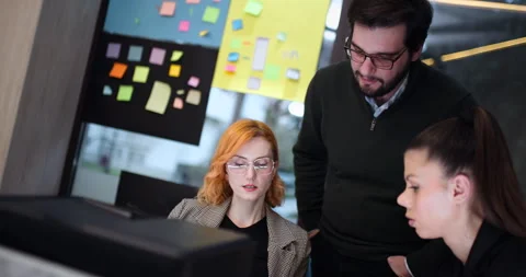 Team members discuss project ideas and work on computer tasks in a shared space Stock Footage 343018994