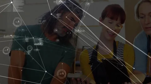 Team members examining tablet in workshop, showing technology network nodes and Stock Footage 307434003