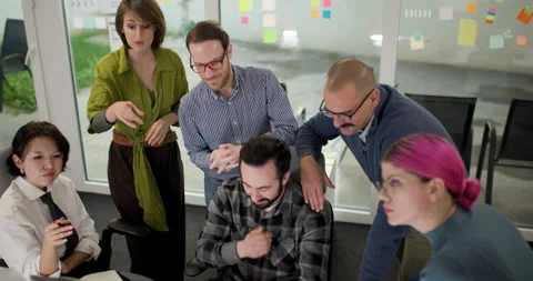 Team members gather around a computer in an office to discuss a project with Stock Footage 338361698