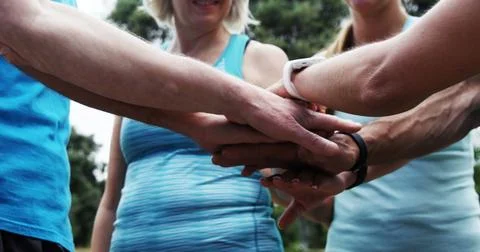 Team members stack hands in a show of unity outdoors Stock Illustration