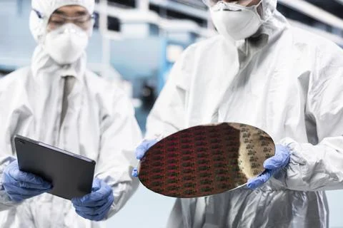 Team of microchip tech professionals inspecting semiconductor substrates Stock Photos