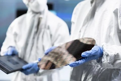 Team of microchip tech professionals inspecting semiconductor substrates Stock Photos
