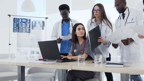 Team of multi ethnic expert doctors examining medical reports at hospital. Group Stock Footage 105974839