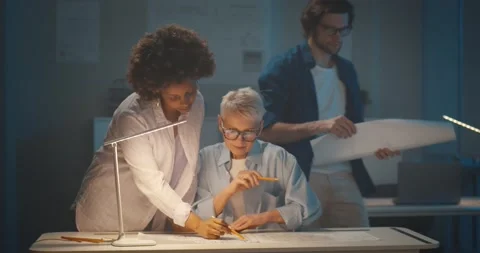 Team of multiethnic architects working on construction plans late in dark office Stock Footage 154149370