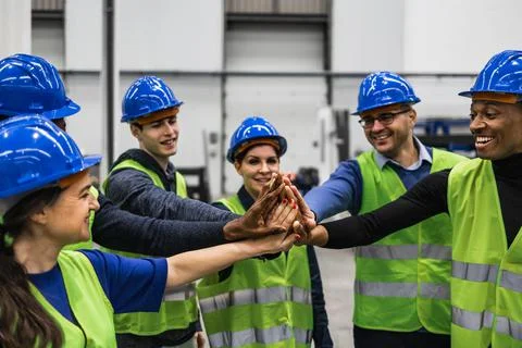 Team of multiracial engineers stacking hands together inside robotic factory 写真素材