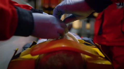 Team of paramedics in gloves giving first aid help to patient in ambulance car Video stock 166910664