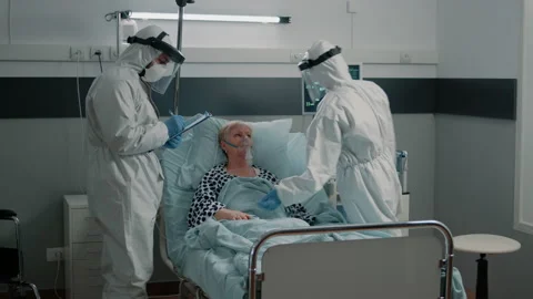 Team of paramedics in hazmat suits checking on patient healthcare Stock Footage 162917335