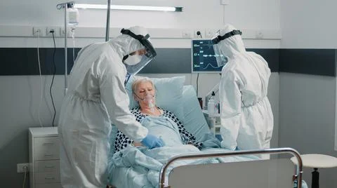 Team of paramedics in hazmat suits checking on patient healthcare Stock Photos