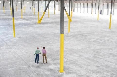 Team of people checking out the new interior of an empty warehouse space. 스톡 사진