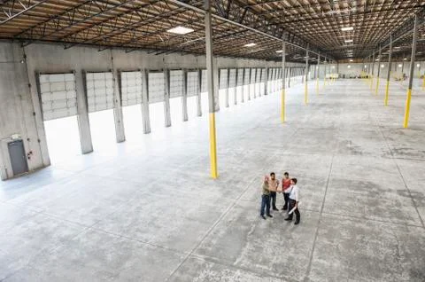 Team of people checking out the new interior of an empty warehouse space. Stock Photos
