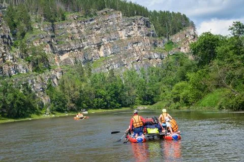 Team of people float down the River on inflatable catamaran among beautiful Stock Photos