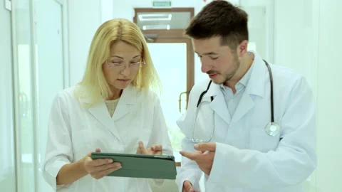 Team of physicians wearing lab coat discussing patient medical test walking in Stock Footage 158382332