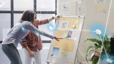 Team pointing to flipchart sticky notes and activating network overlay aligning Stock Footage 333575269