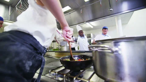 Team of professional chefs preparing and cooking food in a commercial kitchen Stock Footage 31875035