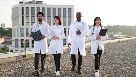 Team of professional experienced multinational doctors walks outside hospital. Stock Footage 262493152