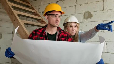 Team of professionals analyzing drawings inside house under construction Stock Photos