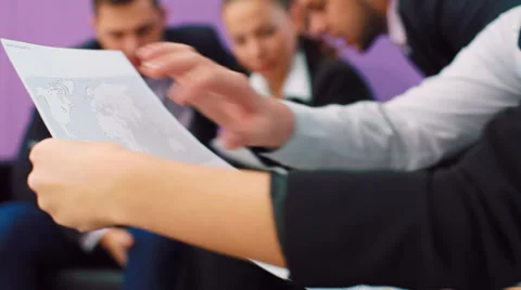 Team of professionals with a world map printouts and other papers Stock Footage 32274581