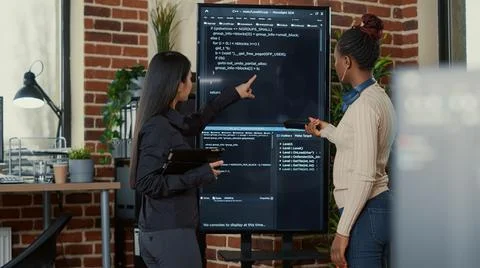 Team of programmers analyzing code on wall screen tv looking for bugs and errors Stockfoto's