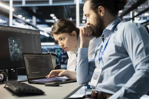 Team of programmers using notebook in server room, analyzing code Foto stock