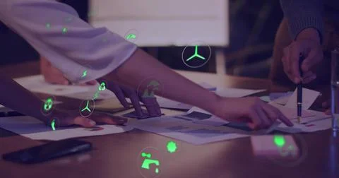Team reaching spreading charts on table, marking energy metrics with green icons Stock Photos