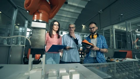 A team of researchers are testing a robotic arm moving objects. Young engineers Stock Footage 127019571
