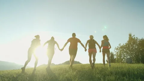 A team of runners running on top of the hill with mountain view holding hands Stock Footage 146669555