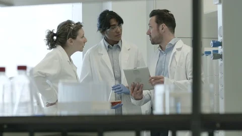 Team of scientists discussing experiment data on digital tablet Stock Footage 74780998