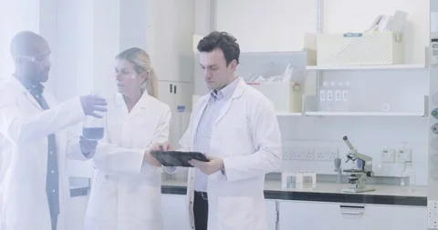 Team of scientists discussing experiment data on digital tablet Stock Footage 123083494