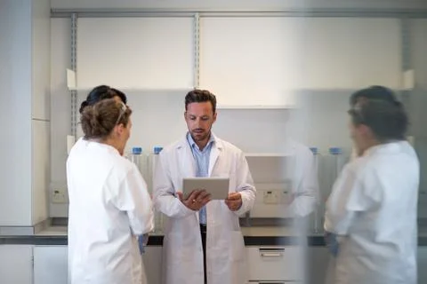 Team of scientists discussing experiment data on digital tablet Stock Photos