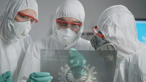 Team of scientists in protective gear looking at image of bacteria Stock Footage 127503980